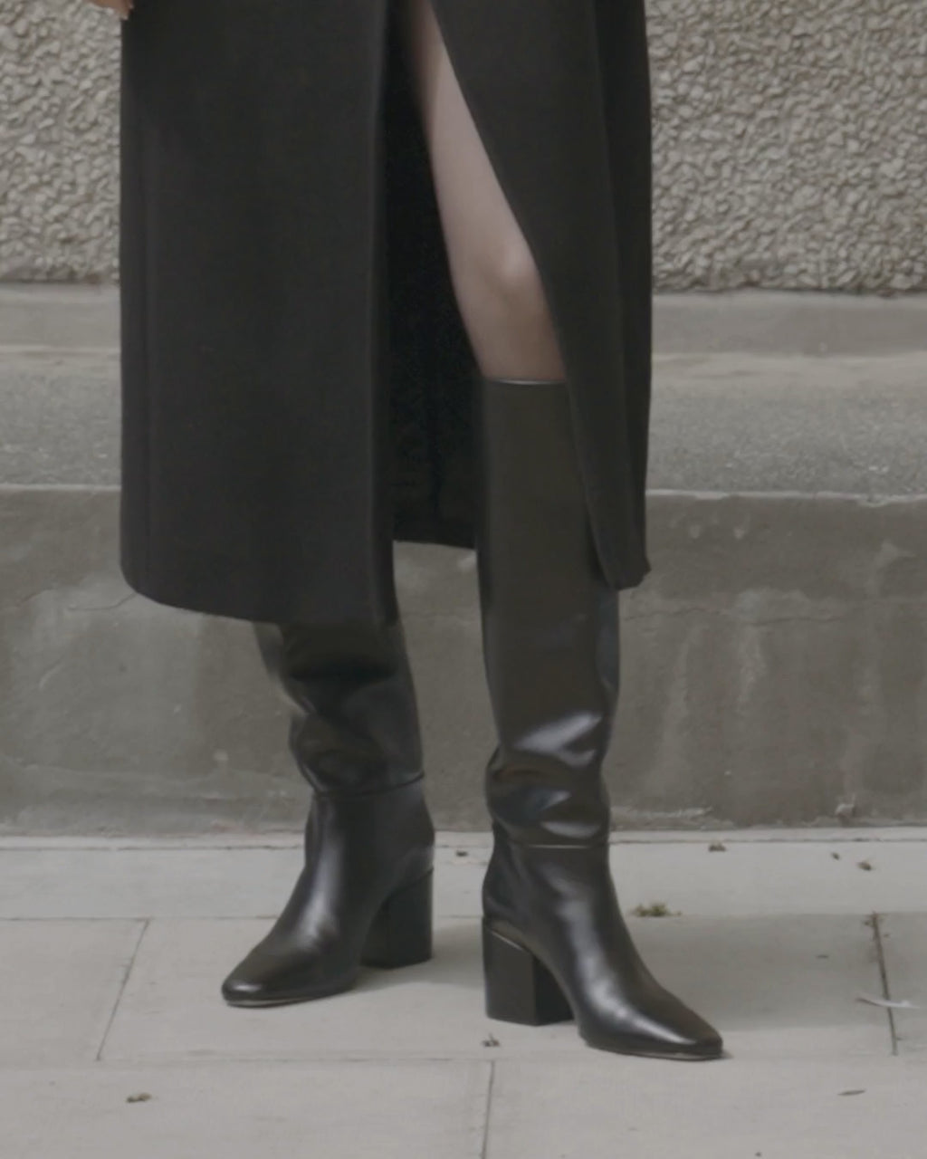Model walking in Dear Frances Alma Knee Boots in black leather, showing the full-height shaft, square toe and block heel